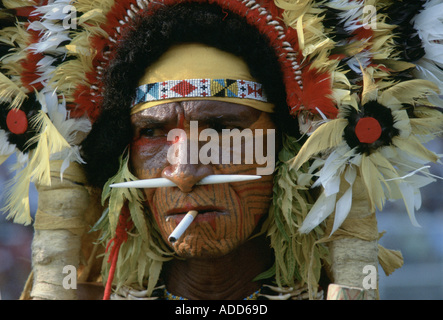 Mann mit Zigarette im Mund und Knochen in der Nase mit zeremonieller Gesichtsfarbe bei Sing Sing Tribal Meeting Papua-Neuguinea Stockfoto