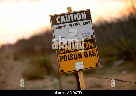Gelbe und weiße Buried Wasserleitung und Giftgas Warnschilder mit Stacheldraht Odessa Texas Stockfoto