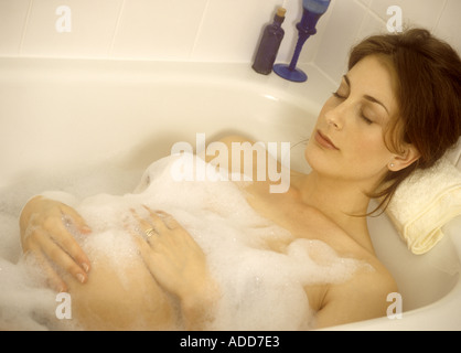 Hochschwangere Frau in einem Schaumbad entspannend Stockfoto