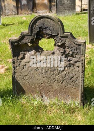 Ein Grabstein so getragen, dass die Inschrift in ein Loch erodiert Stockfoto