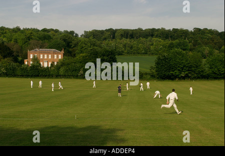 Fielder läuft um der Ball bei einem Cricket-Match auf Hambleden Dorf Spielfeldern, Hambleden zu stoppen. Stockfoto