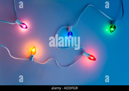 1 schwarze Strang Multi farbige Weihnachtsbaum Lichter durch weißen Hintergrund mit blauer Tönung Studioportrait winken Stockfoto
