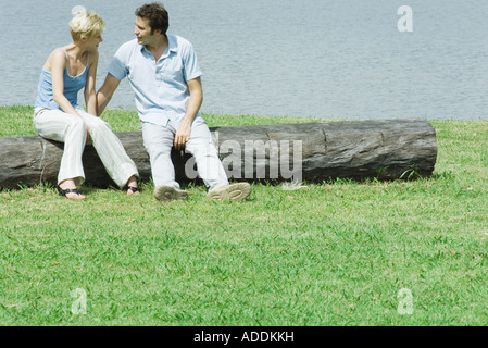 Paar sitzend auf Baumstamm, sprechen Stockfoto