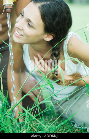 Frau aus outdoor Wasserhahn trinken Stockfoto