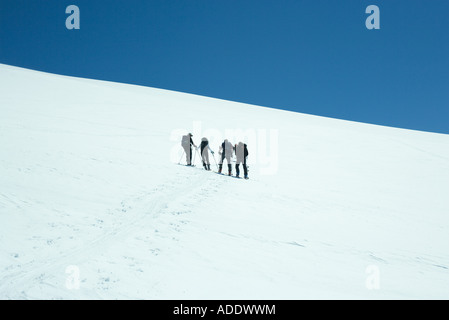 Skifahrer, die nebeneinander stehen, am Hang, Rückansicht Stockfoto