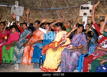 Ost-indischen Frauen in bunten Sariis halten Hände sitzen im Halbkreis auf Tagung im Reetdach Zimmer in Indien Stockfoto