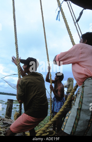 Ost-indischen Männer arbeiten als Team ziehen Seile und Hebel und Gewichte am chinesischen Fischernetze in Cochin Kochi Kerala Indien Stockfoto