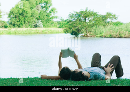 Paar, liegen auf dem Rasen in der Nähe von See, lesen Stockfoto