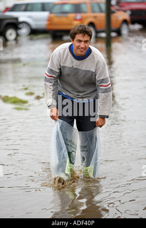 Boy spritzt durch überschwemmte Feld mit Plastiktüten auf seinen Füßen nach starkem Regen in der Nähe von Turriff, Aberdeenshire, Schottland, UK Stockfoto