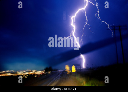 Ein Blitz stürzt sich direkt an der Autobahn bei einem Sturm. Lichter verwischen der Vordergrund in diesem Windschutzscheibe geschossen. Stockfoto