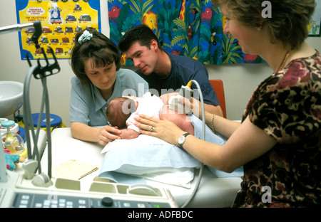 Kleinen Neugeborenen mit ultra sound Scann im Krankenhaus, während Mutter und Vater unterstützend auf schauen. Stockfoto