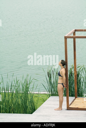 Frau mit Bikini, Holzkonstruktion, in der Nähe von See gelehnt Stockfoto
