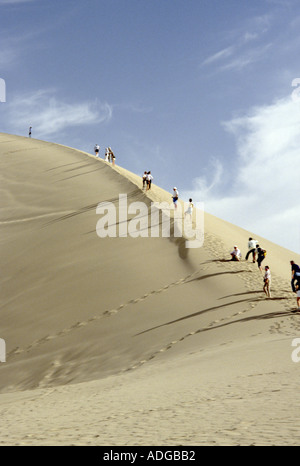 Touristen Klettern auf einer Sanddüne in Dunhuang Gobi Wüste, China Stockfoto
