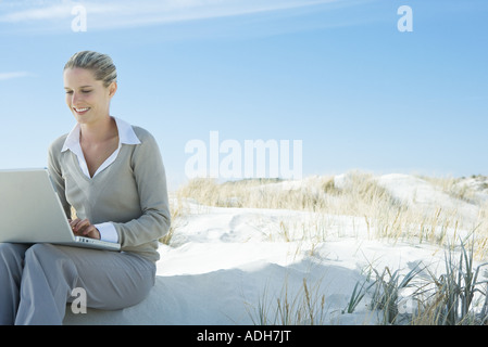 Geschäftsfrau sitzen am Strand, mit Laptop, wegschauen Stockfoto