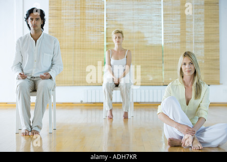 Gruppenmeditation, Erwachsene sitzen in verschiedenen Positionen Stockfoto