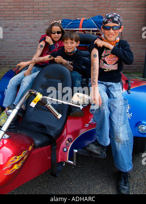 Drei stolze Kinder zeigen ihre Fake tattoos Harley Davidson sitzend auf ihre Väter Trike Breda Niederlande Stockfoto