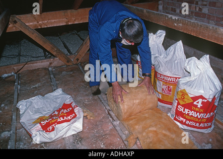 Generator mit Overall und die passende Maske rollt Superwrap Faser Glas Dachdämmung im Dach-Raum UK Stockfoto