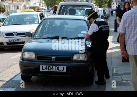 Traffic Warden schreiben einen Parkplatz ticket Gesetzeshüter Stockfoto