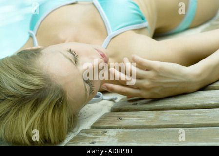 Junge Frau, die vom Rand des Pools liegt Stockfoto