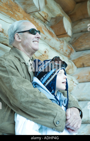 Junge und Großvater stehen in der Nähe von Blockhaus, wegschauen Stockfoto