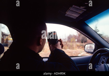 Polizist in Kreuzer mit einem handheld Laser messen die Geschwindigkeit der Autofahrer sitzen. Kansas City, MO, PD, USA. Stockfoto