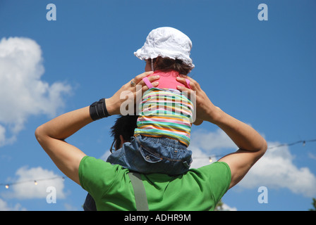 kleines Kind mit Sonnenhut auf Vaters Schultern sitzen Stockfoto