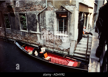 Gondoliere nimmt sich eine Auszeit von der Arbeit in einem hinteren Kanal in alten Venedig Italien Stockfoto