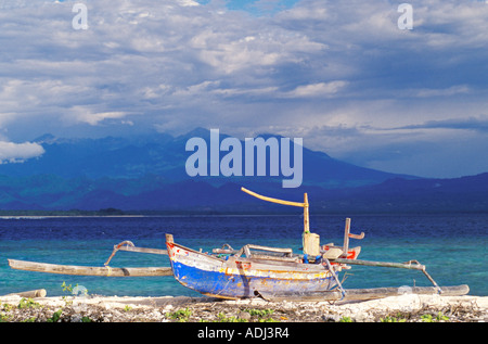 Ein Katamaran sitzt an einem Strand in Indonesien mit einem 11.000 Fuß Vulkan in der Ferne. Stockfoto