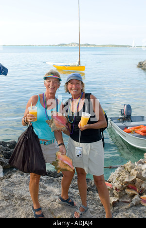 GREAT EXUMA BAHAMA GEORGE TOWN Frauen Touristen hält Muscheln und tropische Drinks in Elizabeth Bay Harbour Stockfoto