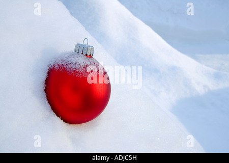 Rote Christbaumkugel in einer frischen Schneedecke bedeckt in Snowbank Winter Alaska platziert Stockfoto