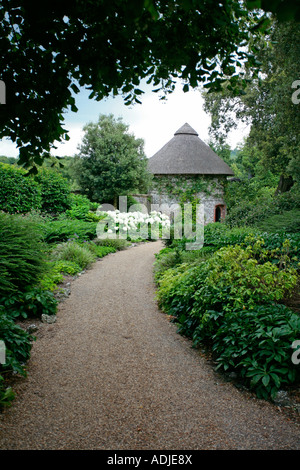 Weg durch den Garten führt zum runden strohgedeckten Sussex Feuerstein Torheit. West Dean Gardens, Sussex, UK Stockfoto