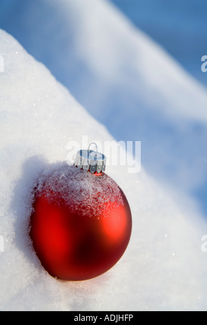 Rote Christbaumkugel in einer frischen Schneedecke bedeckt in Snowbank Winter Alaska platziert Stockfoto