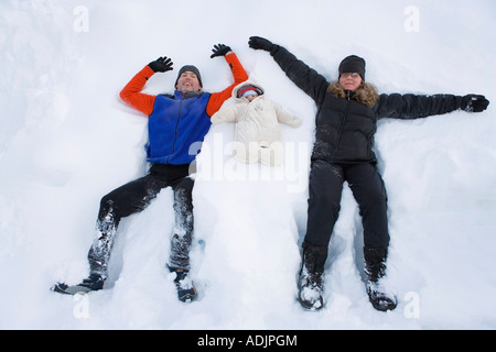 Familienbild von zwei Eltern und ein Kind für den Winter im Schnee Engel Position Yunan Alaska liegen gebündelt Stockfoto