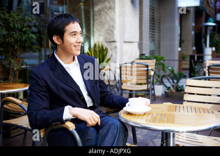 Ein lächelnder Mann sitzt in dem Straßencafé Stockfoto