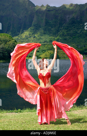 Bauchtänzerin mit roten Schleier ausgestreckten in tropischer Umgebung Stockfoto