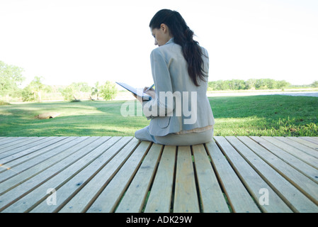 Geschäftsfrau, die sitzen auf decking, schreiben Stockfoto