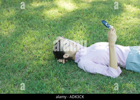 Geschäftsfrau im Grass liegen Blick auf Handy Stockfoto