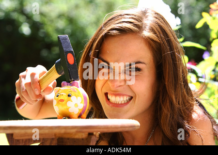 Junge Frau raubt ein Sparschwein mit einem Hammer © Peter Schatz/Alamy Stockfoto