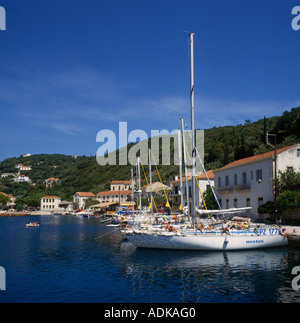 Hafen von Nebengebäuden mit weißen Yachten vor Anker und Menschen im Liegestuhl an Bord in Kioni Ithaca Insel der griechischen Inseln Griechenland Stockfoto