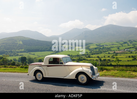 Oldtimer-Tourer auf der Trassey Straße durch die Mourne Mountains, County Down, Irland mit Slieve Bearnagh in der Ferne. Stockfoto