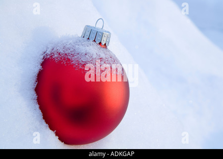 Rote Christbaumkugel in einer frischen Schneedecke bedeckt in Snowbank Winter Alaska platziert Stockfoto