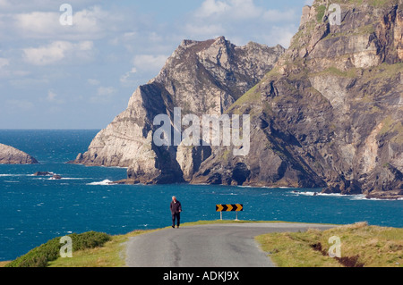 Mann zu Fuß auf der Straße nach Süden aus Glencolmcille, Malin Beg, Südwest County Donegal, Irland. Klippen von Glen Kopf hinter. Stockfoto
