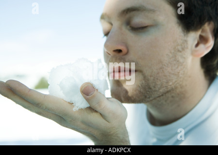 Junger Mann mit Schneeball in der hand, Augen geschlossen Stockfoto