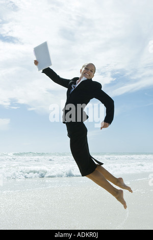 Geschäftsfrau in Luft am Strand, springen in die Kamera Lächeln Stockfoto