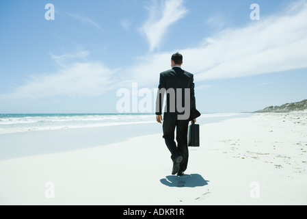 Geschäftsmann zu Fuß am Strand, mit Aktentasche Stockfoto