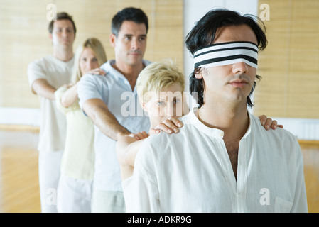 Gruppentherapie, stehend im Gänsemarsch Linie mit den Händen auf die Schultern, Mann mit verbundenen Augen führen Stockfoto