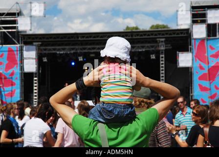 kleines Kind mit Sonnenhut auf Vaters Schultern Festival Aufführung sitzen Stockfoto