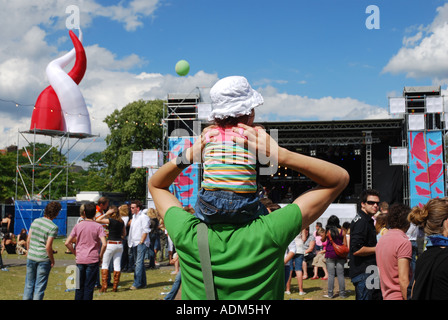 kleines Kind mit Sonnenhut auf Vaters Schultern Festival Aufführung sitzen Stockfoto