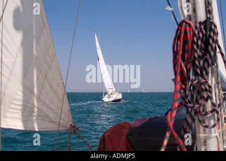 Blick auf einem Segelboot aus auf dem Deck des anderen, umrahmt von Mast und Segel. Stockfoto