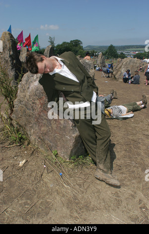 Ein Punter gekleidet in einen Smoking, Einschlafen am Steinkreis. Glastonbury Music Festival 2005. Stockfoto